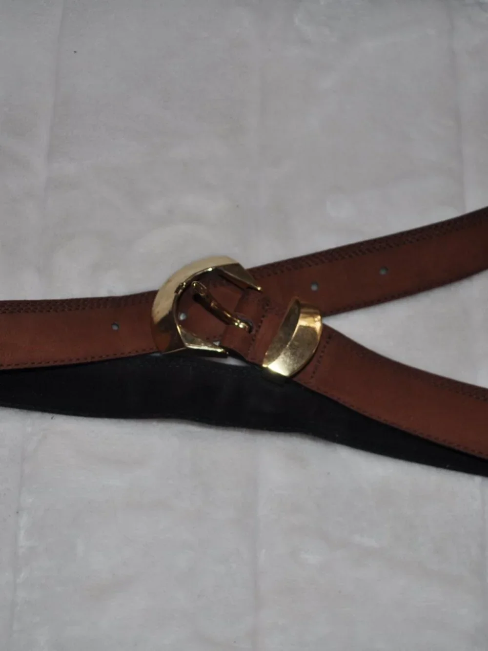 Women's belt features distinctive gold-tone metal hardware, including a unique